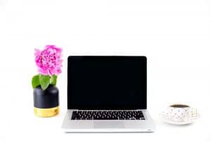 laptop on desk with flowers and cup of coffee