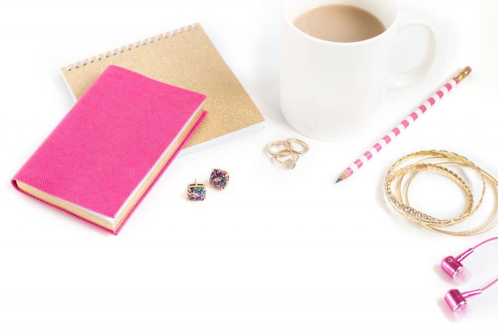 Flatlay image with notebook, envelope, pencil, coffee cup and jewelry