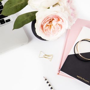 White and black laptop, pink peonies, notebooks and pen