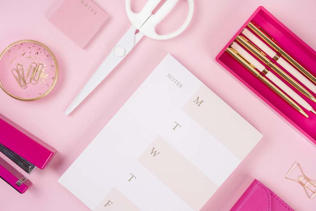 pink desktop with calendar, scissors, and pens