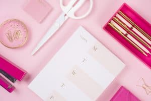 pink desktop with calendar, scissors, and pens