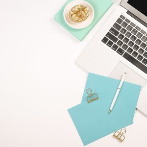 white laptop, notecard and evelope, pen, and paperclips