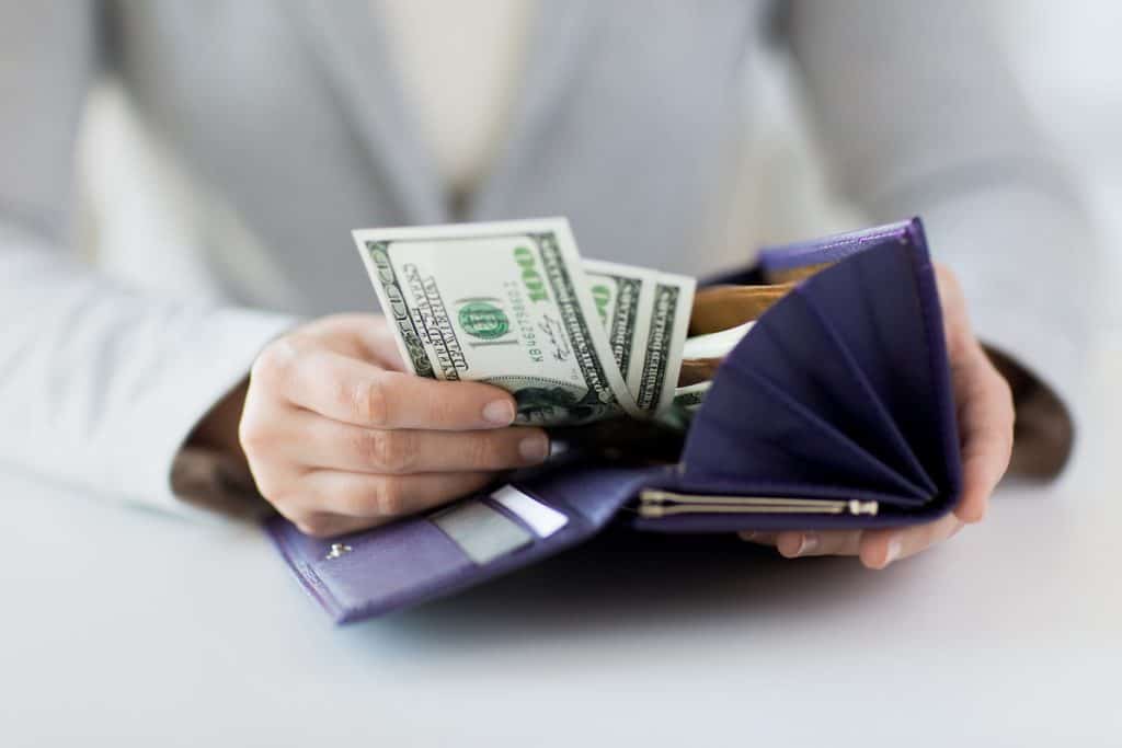 woman reaching for cash in purple wallet