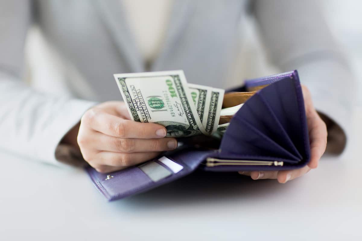 Woman reaching for cash in purple wallet