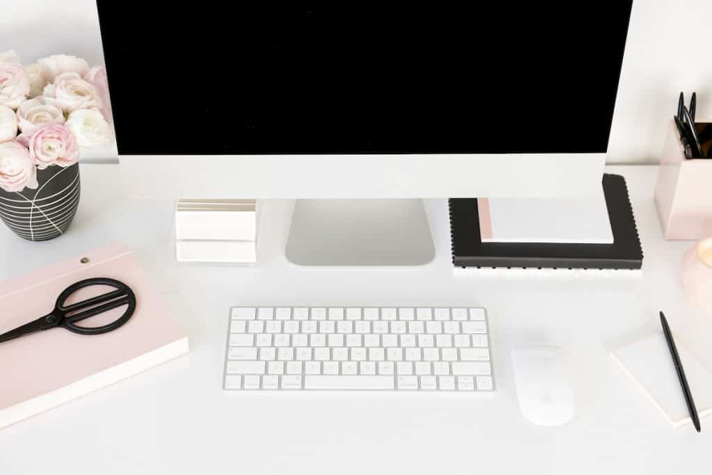 Feminine image of desktop conmputer, journals, flowers, scissors