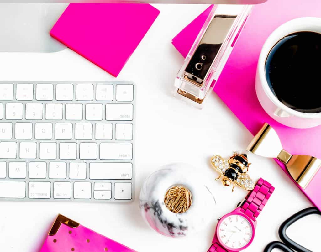white keyboard, pink leather journal, watch and coffee cup