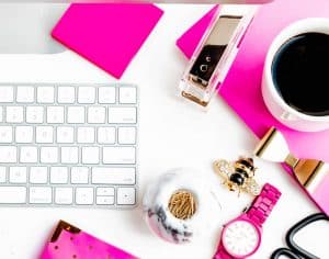 white keyboard, pink leather journal, watch and coffee cup