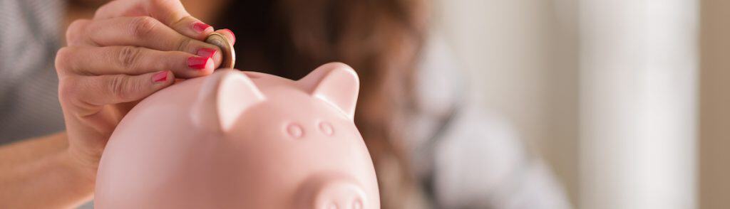 woman putting coin in piggy bank for example image in how to live cheaply article