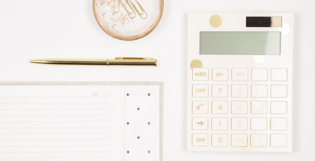 desk with a gold calculator for the featured image in the post difference between rich and wealthy