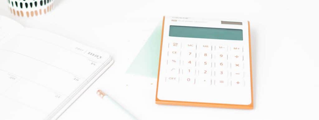 white calculator on a desk used as featured image for the digit vs acorns app review