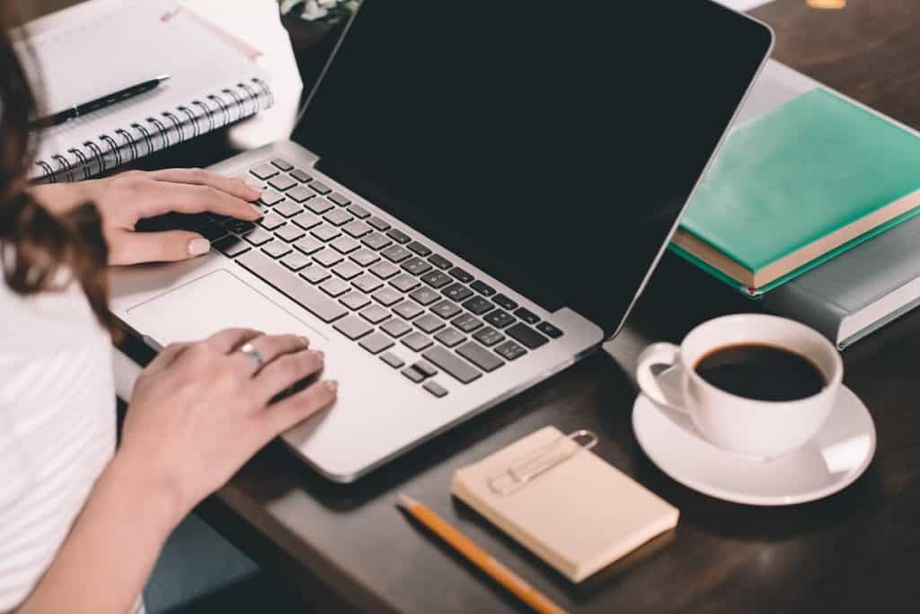 laptop on a desk with a woman's hand typing on it