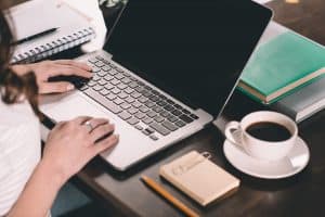 laptop on a desk with a woman's hand typing on it