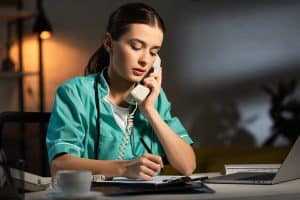 nurse working from home with laptop and phone